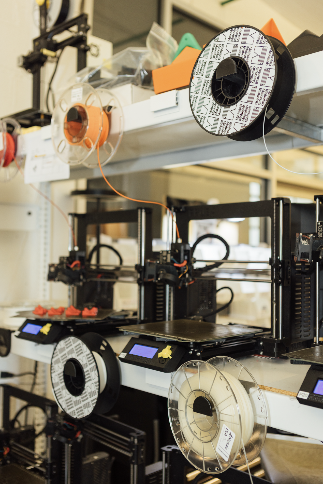 Two rows of 3D printing materials on a shelf of similar materials.